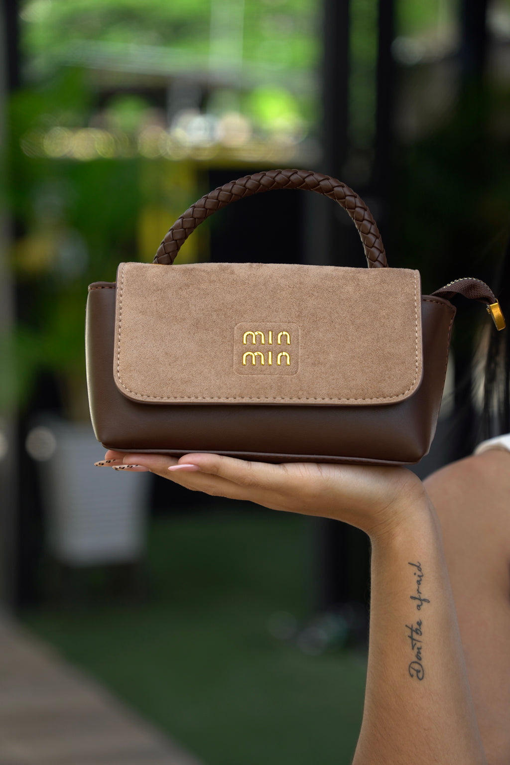 Mujer sosteniendo mini baúl FALLON café beige con outfit blanco - CALÉA