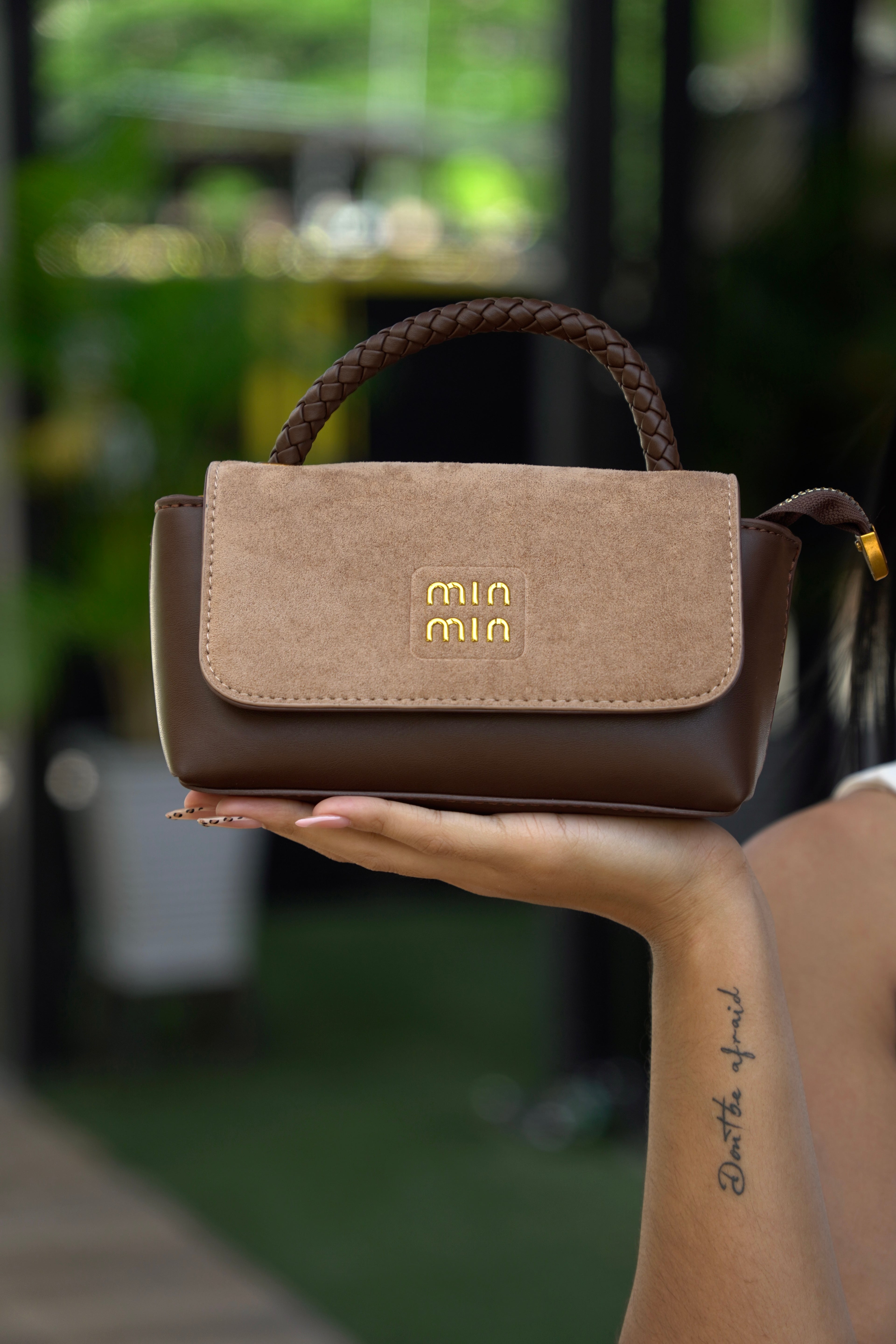 Mujer sosteniendo mini baúl FALLON café beige con outfit blanco - CALÉA