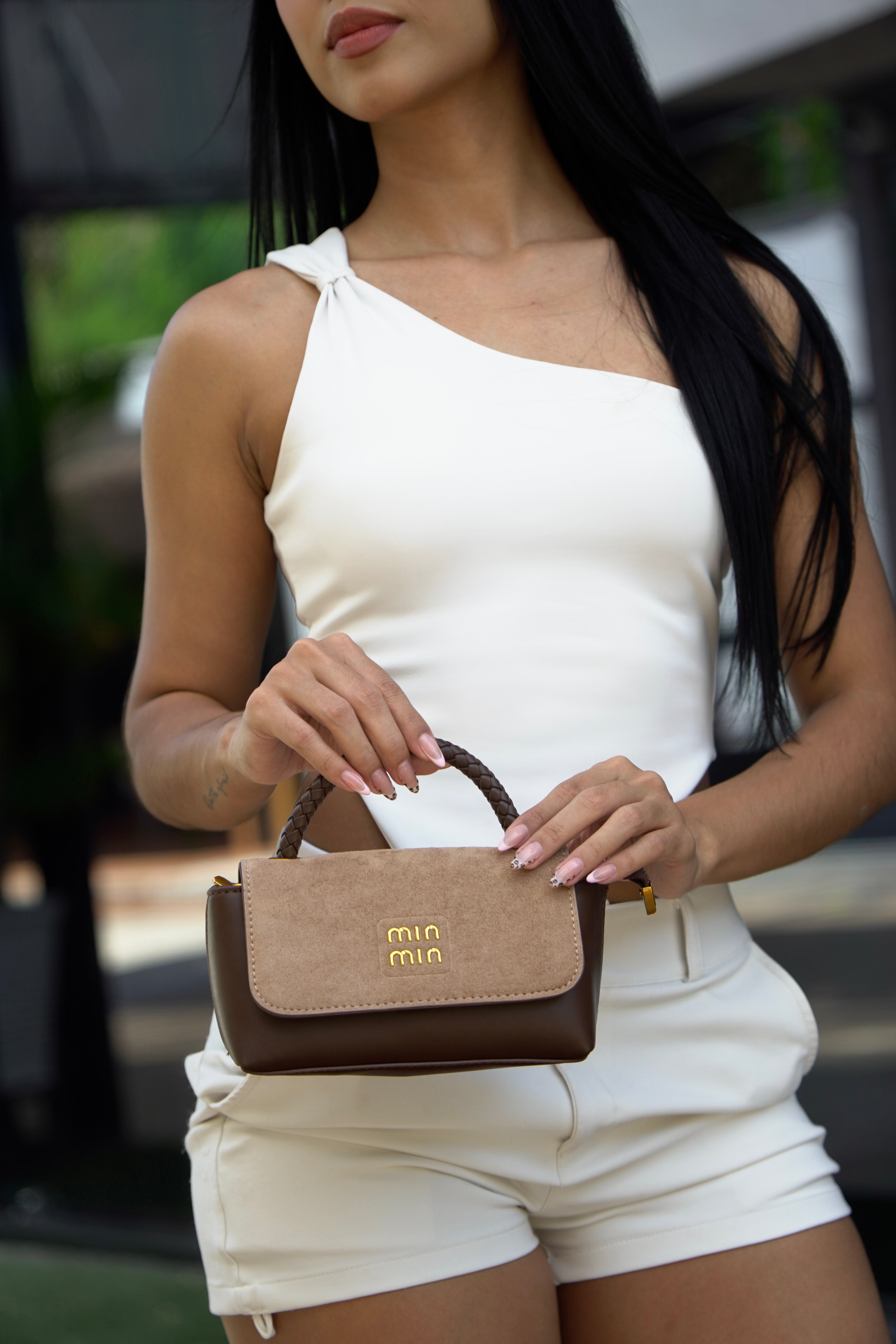 Detalle de mini bolso FALLON gamuza café beige en manos - CALÉA