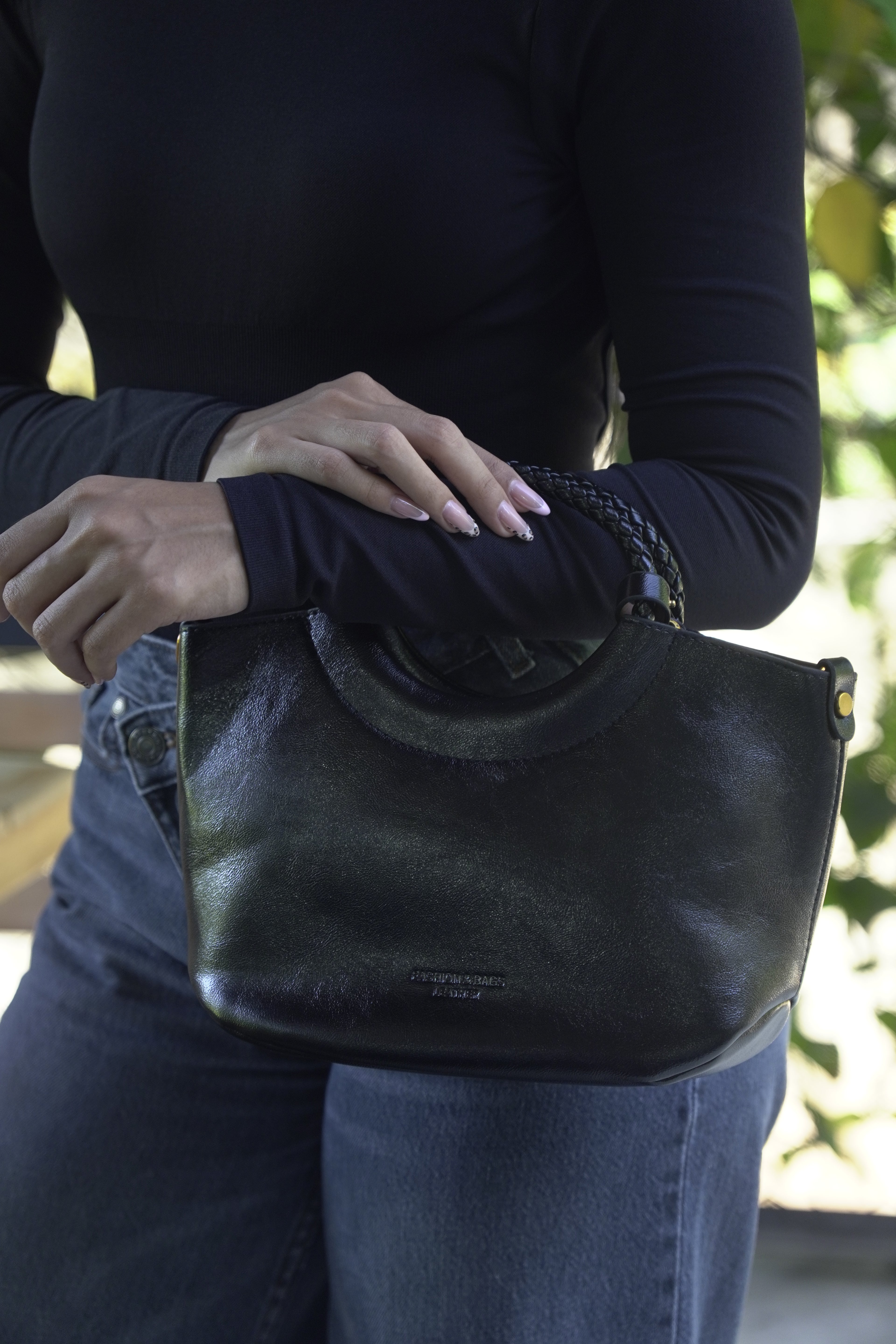 Detalle de bolso FRANCESCA negro con asa trenzada en mano - CALÉA