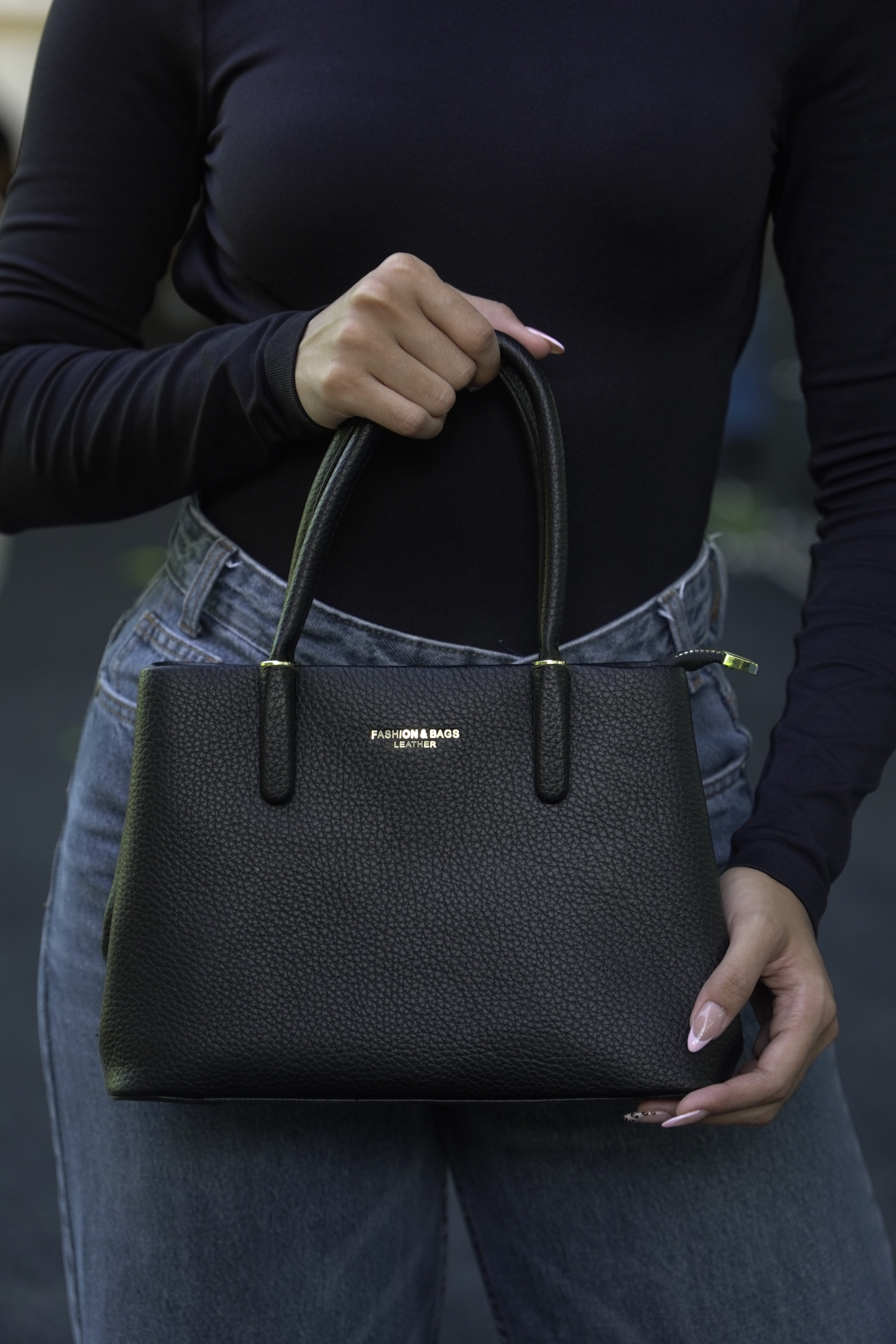 Detalle de bolso tote ROMA negro sostenido en mano - CALÉA